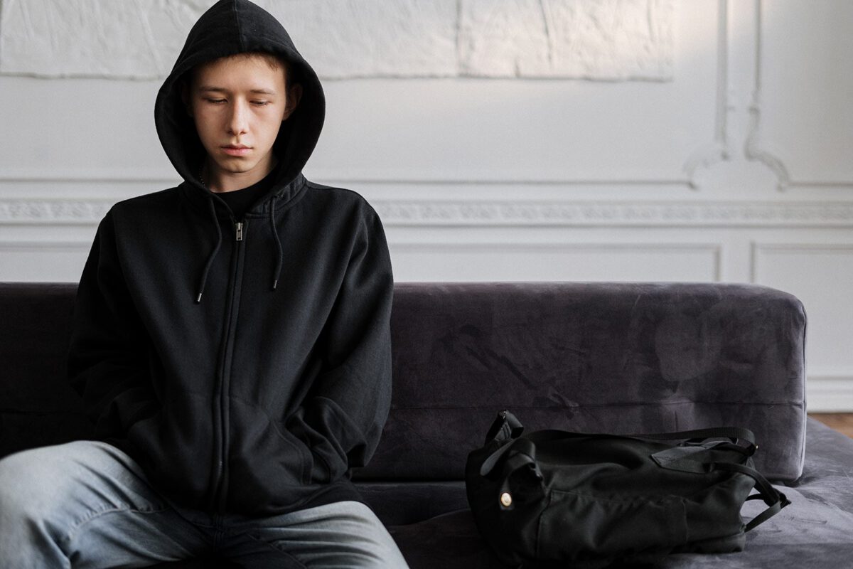 Teen in black hoodie sitting on couch