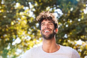 Close up portrait of laughing handsome man with beard outside in nature